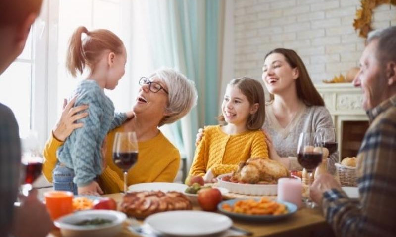 Family gathered and laughing at the dinner table for a holiday meal.