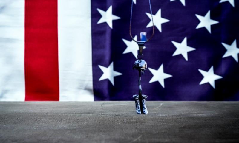Battle cross pendant urn necklace with American Flag backdrop.