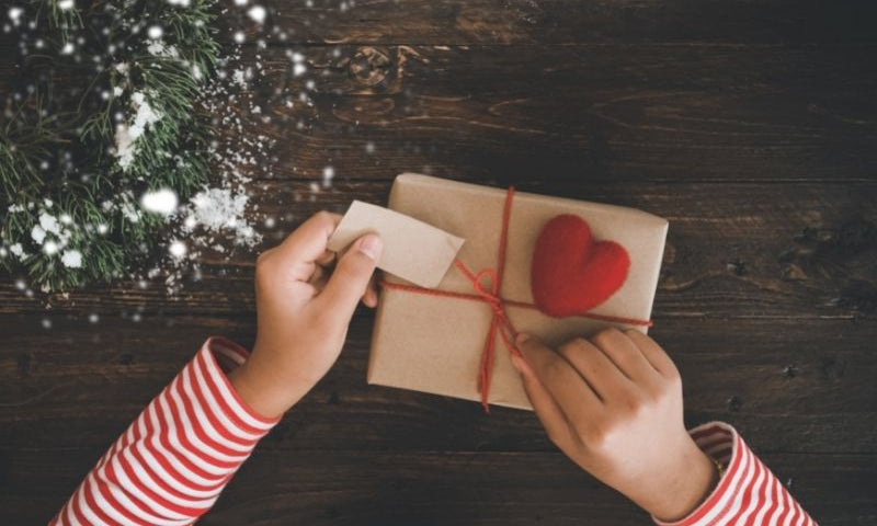 Unwrapping a Christmas gift wrapped in brown paper.